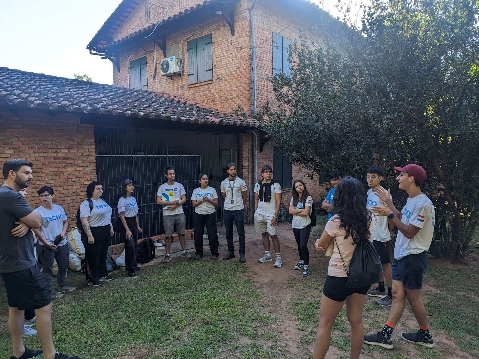 Deriv Asunción and TECHO teams forming a circle while discussing the CSR initiative.