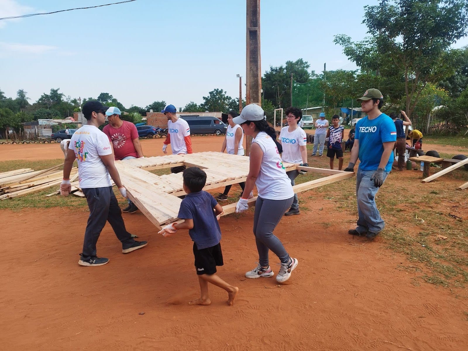 A young boy helping the Deriv Asunción and TECHO employees unloading building materials. 