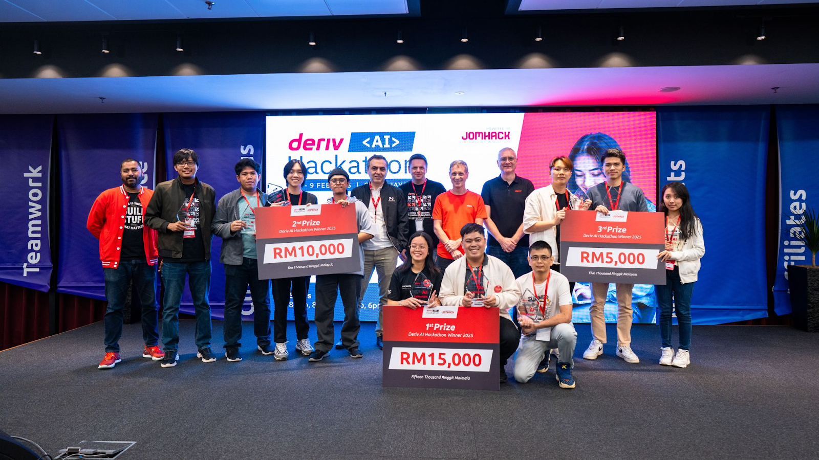 Winners of Deriv’s second AI Hackathon celebrating on stage, holding prize cheques for RM15,000, RM10,000, and RM5,000.